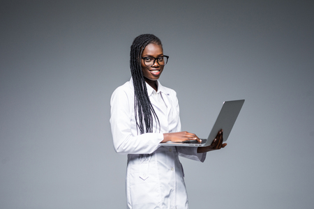 Beautiful African American woman doctor or nurse holding a laptop computer isolated on a white backgroundの写真素材