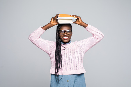 Portrait of an african girl holding book on her head and looking away at copy space isolated over gray backgroundの写真素材