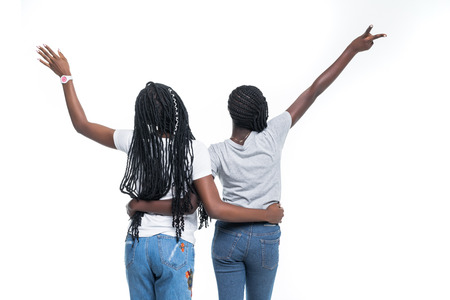 Rear view of two african women with raised hands over white background.の写真素材
