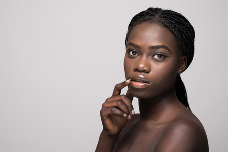 Beautiful Young african Woman with clean Fresh Skin touch own face . Facial treatment. Cosmetology.の写真素材
