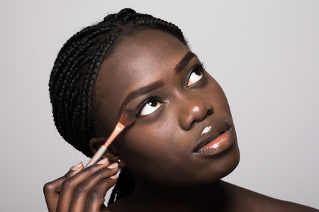 Portrait of beautiful woman applying cosmetic isolated on beigeの写真素材