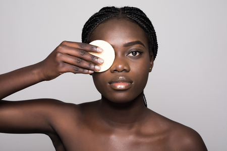 Portrait of beautiful young woman applying foundation, isolated on whiteの写真素材