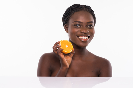 Beautiful young african american woman isolated on white background. Afro girl and diet concept with orange fruit. Copy space. Mock up. Skin care, spa and make up concept.の写真素材