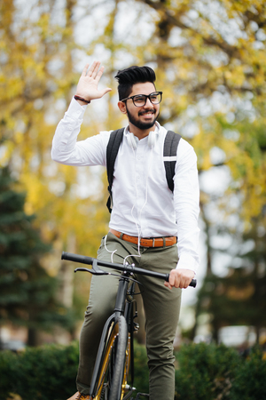Casual handsome businessman going to work by bicycle. He is riding bike and waving Hello.の写真素材