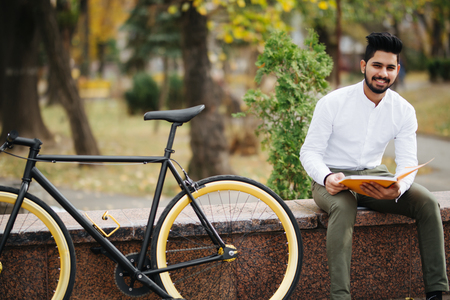 Young man reading a book while taking a break on the city streetの写真素材