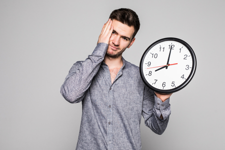Portrait of a smiling man sad becouse late holding wall clock over gray backgroundの写真素材