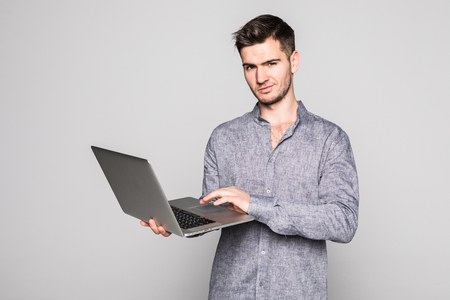 Cheerful man with a laptop isolated on gray backgroundの写真素材