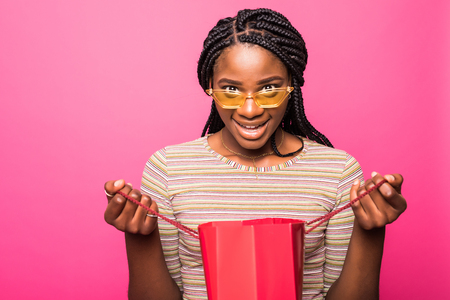 Portrait of beautiful african american girl looking into shopping bag with surprised expression on faceの写真素材