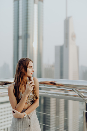 Young pretty woman drink white wine and enjoy the amazing view of Dubai downtown.の写真素材
