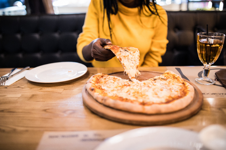 Young african american woman eating pizza in cafeの写真素材