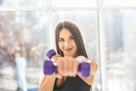 Muscular young woman with beautiful body doing exercises with dumbbell.の写真素材