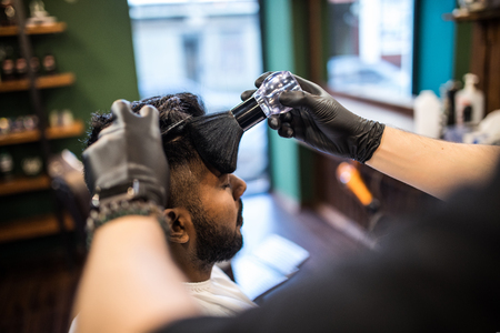 Close up of hairstylist trimming senior client hairの写真素材