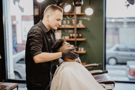 Hairstylist applying after shaving lotion in barber shopの写真素材