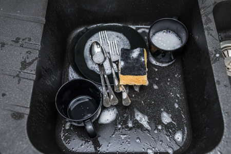 dirty dishes in a kitchen sink at homeの写真素材