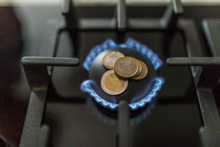 Cost of gas, concept crisis. Gas stove with coins in flame. The cost of methane. Gas coins more expensiveの写真素材