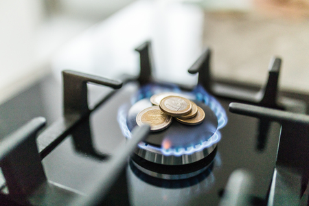 Cost of gas, concept crisis. Gas stove with coins in flame. The cost of methane. Gas coins more expensiveの写真素材