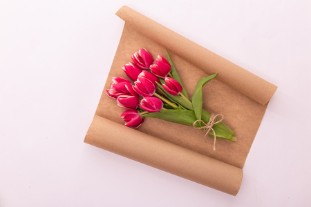 top view of beautiful pink tulips bouquet in wrapping paper, ribbons on white backgroundの写真素材