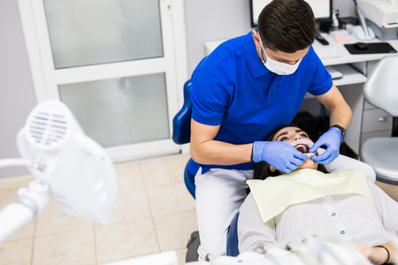 Man dentist and woman patient during the process of teeth whiteningの写真素材