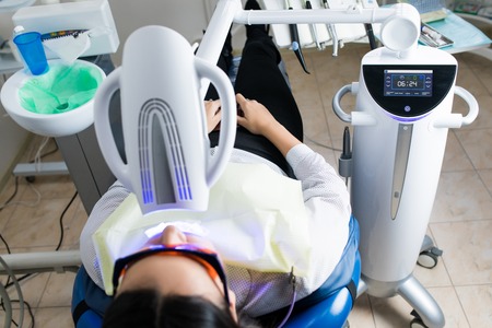 Portrait of young woman visiting dentist office for teeth whitening with photopolymerの写真素材