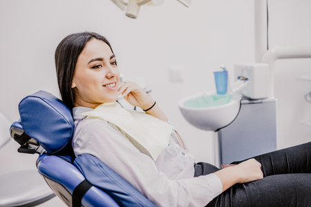 Young female patient visiting dentist office.Beautiful smiling woman with healthy straight white teeth sitting at dental chair.Dental clinic.Stomatologyの写真素材