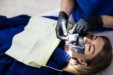 A latex plate designed to isolate the tooth to be treated from the rest of the oral cavity during treatment. Dentists prepare a tooth to install a seal.の写真素材