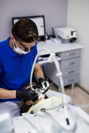 Man at dentist clinic gets dental treatment to fill a cavity in a tooth. Dental restoration and composite material polymerization treat of teeth.の写真素材