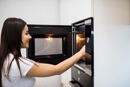 Beautiful young woman checking how her cake is doing in the oven