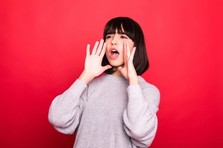 Woman shouting and announcing something on red backgroundの写真素材