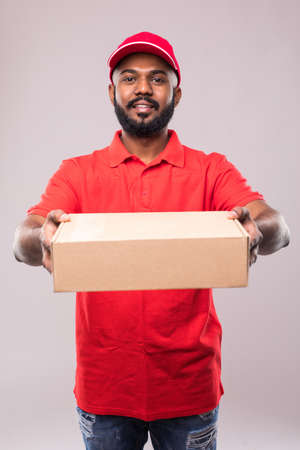 Side view of young delivery man with box. isolated gray background