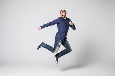 Full length portrait of happy excited bearded man jumping and looking at camera isolated over white backgroundの写真素材
