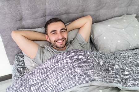 Handsome man lying in bed and looking at the camera