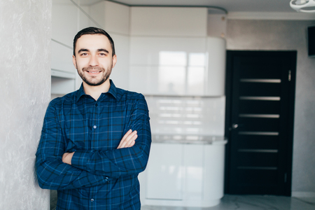 Portrait of confident young man standing by kitchen counterの写真素材