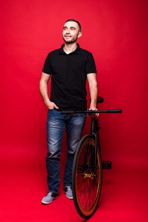 Handsome young man with bicycle on red backgroundの写真素材