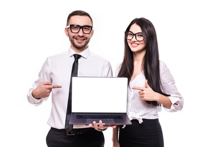 Portrait of smiling happy business couple pointing at blank screen laptop computer while standing...