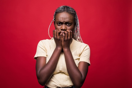 Headshot of beautiful scared young dark-skinned European woman closing mouth not to scream, feeling...