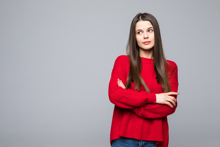 Portrait of doubting popular european woman in red loose sweater and careless expression, being disappointed or unimpressed over gray wallの写真素材
