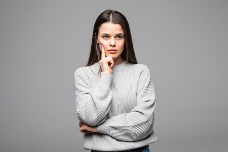 Smiling woman wearing sweater standing against isolated gray background. Crossed arms. Fashion portrait of casual dressed woman in warm clothes.の写真素材