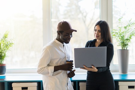 African business man and caucasian woman with laptop in modern business center.の写真素材