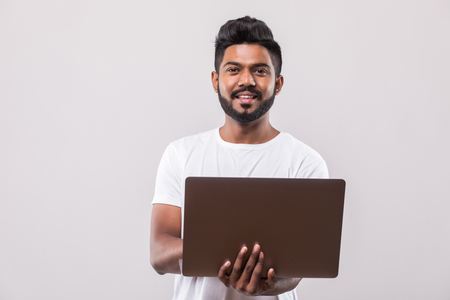 Confident young handsome man in shirt and tie holding laptop and smiling while standing against white backgroundの写真素材