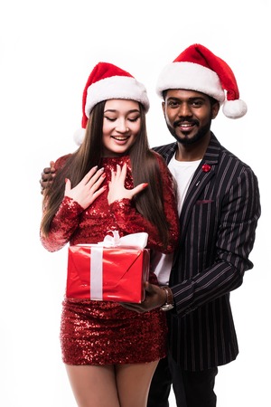 A happy couple of lovers, in Santa Claus hats, celebrates the New Year, with Christmas gifts in their hands. On a white background.の写真素材