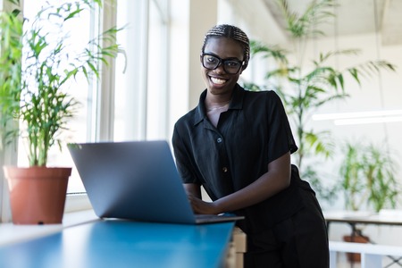 Close up portrait of beautiful young woman smiling and looking at laptop screenの写真素材