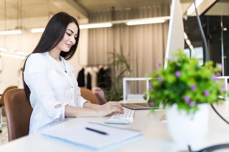 Portrait of businesswoman using computer at office deskの写真素材