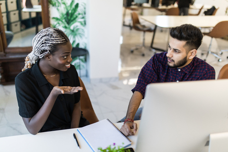 Indian Businessman and african businesswoman working with pc at officeの写真素材