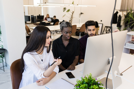 Focus on positive caucasian confident team leader mentor use computer sitting together with diverse...