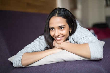 Close up portrait of a pretty lovely woman lying on a couch and laughing indoors