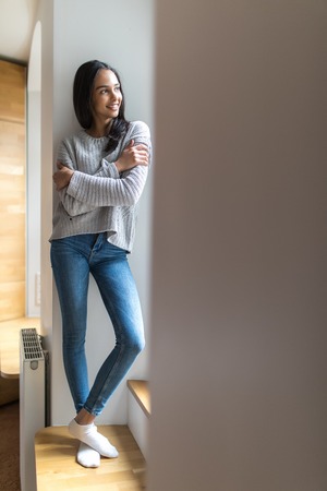 Young woman standing near window at homeの写真素材