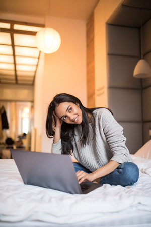 Young woman using laptop on bedの写真素材