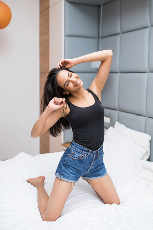 Happy young woman in earphones is listening to music with smart phone, dancing and smilingの写真素材