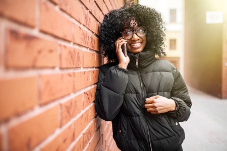 Portrait of pretty black woman in urban background talking on phoneの写真素材