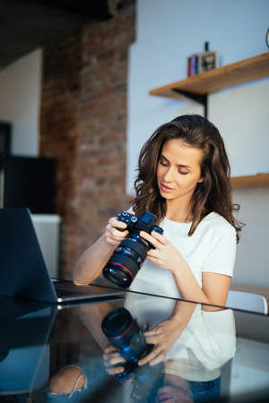 Freelance photographer woman with camera at home editing photos on computerの写真素材